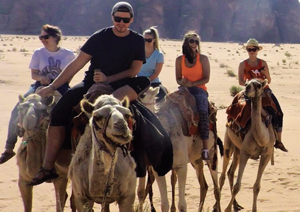 Joshua Brown and other students riding camels